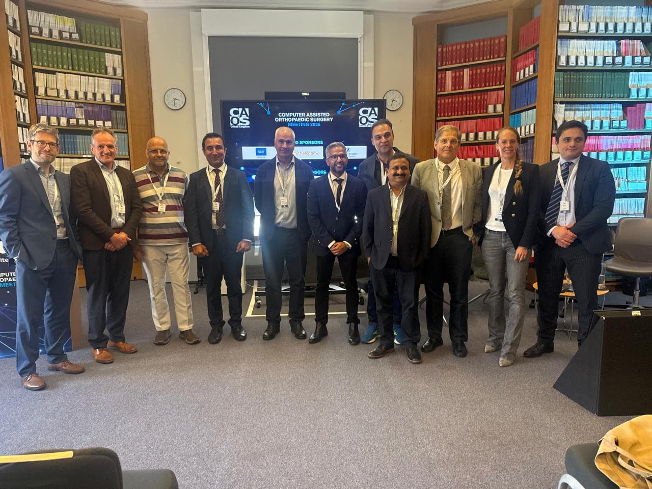 Dr Mujahid Jamil Khattak with the faculty and delegates in a group photograph in front of the Computer Assisted Orthopaedic Surgery Meeting 2026 screen in London
