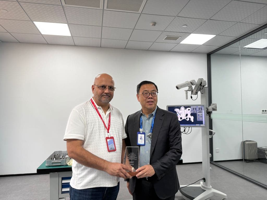 Dr Mujahid Jamil Khattak receiving a commemorative shield from the host alongside a surgical navigation system in China